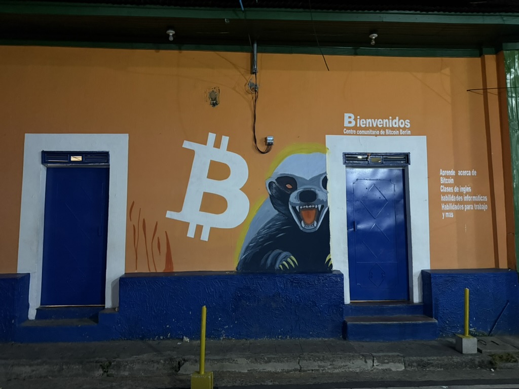 Orange facade of the Bitcoin Community Center in Berlín, with a Bitcoin symbol and honey badger mural.